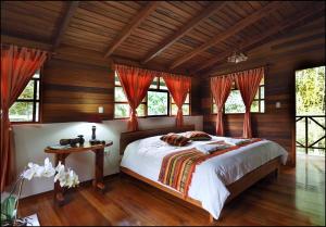ein Schlafzimmer mit einem großen Bett mit roten Vorhängen in der Unterkunft Rio Quijos EcoLodge in El Chaco