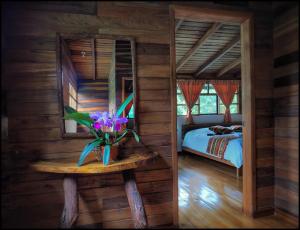 ein Schlafzimmer mit einem Bett und einem Tisch mit einer Blumenvase in der Unterkunft Rio Quijos EcoLodge in El Chaco