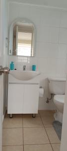 Un baño blanco con lavabo e inodoro. en Departamento Balneario Pelluco, en Puerto Montt