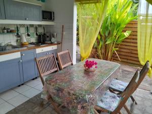 tavolo e sedie in cucina con tavolo e ciotola di fiori di Bungalow papaye a Sainte-Anne