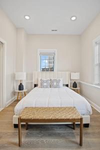 a white bedroom with a large bed and a bench at Loopin Around Atlantic City Luxe 5BR Townhouse in Orange Loop in Atlantic City +29 photos