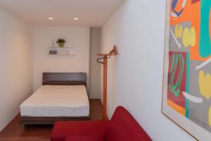 a small room with a bed and a red couch at Meguru坪井2 in Kumamoto