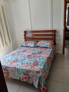 a bed with a floral bedspread and pillows on it at Casa e conforto in Itapoa +11 photos
