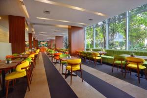 a restaurant with yellow chairs and tables and windows at Somerset Kencana Jakarta in Jakarta