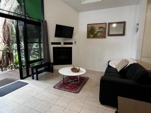 a living room with a black couch and a table at Gallery Walk Chalets - Tamborine Mountain in Mount Tamborine +43 photos