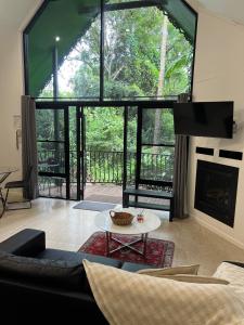 a living room with a fireplace and a large window at Gallery Walk Chalets - Tamborine Mountain in Mount Tamborine