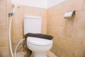 a bathroom with a white toilet in a room at Enjoy Living and Warm Studio at Serpong Garden Apartment By Travelio in Tangerang