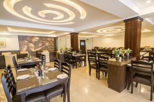 ガントクにあるDaizzo Hotelsのテーブルと椅子があり、天井が高いレストラン