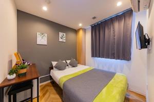 a bedroom with a bed and a desk and a window at JA Hotel Tennoji in Osaka