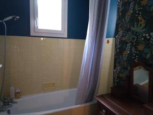 a bathroom with a tub and a shower curtain at Maison de village proche du Lac de Vassivière in Peyrat-le-Château +15 photos