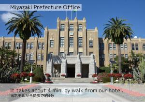 a large building with palm trees in front of it at K's Street Hotel Miyazaki in Miyazaki