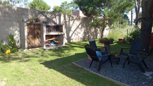 Un patio trasero con sillas, una mesa y una chimenea. en Casa con Patio y Parrilla Zona Golf, en Villa Gesell
