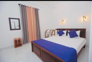 a bedroom with a large bed with blue pillows at Hide Hiriketiya Villa in Dickwella
