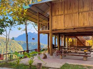a wooden building with benches and mountains in the background at Pu Luong - Duy Phuong Homestay in Thanh Hóa