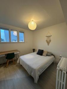 a bedroom with a bed and a desk and windows at Repère cosy in Saint-Brieuc