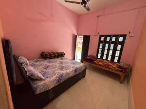a bedroom with pink walls and a bed and a window at Chandrakala Ashram in Naimishāranya +3 photos