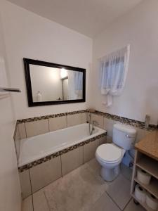 a bathroom with a tub and a toilet and a sink at Easy Breezy at 18 Thira Santorini in Ballito
