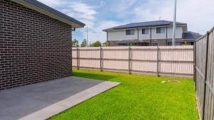 a backyard with a fence and a grass yard at Luxury 7 Bedroom Home - Sleeps 16 Guests in Gledswood Hills