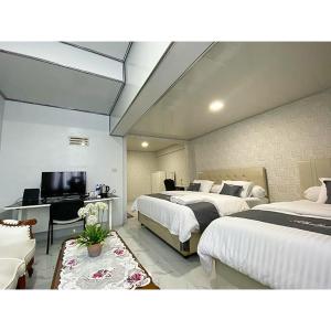 a bedroom with two beds and a desk and a television at Athallah Homestay Syariah in Lampung