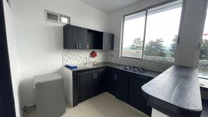 a kitchen with black cabinets and a sink and a window at Villa Carolina Casa Campestre in Montenegro