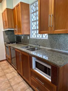 a kitchen with wooden cabinets and a sink at Tipani Villa Sovereign Palms CI in Rarotonga