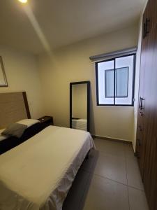 a bedroom with a large bed and a window at Depa los robles fracc aldea hortus in Naranjo
