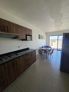 a kitchen with wooden cabinets and a table with chairs at Depa los robles fracc aldea hortus in Naranjo