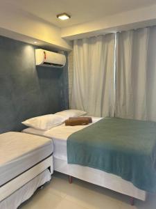 a room with two beds and a window at Apt Maracaipe, Porto de Galinhas in Porto De Galinhas