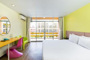 a hotel room with a bed and a desk and a window at Bella Express in Pattaya Central