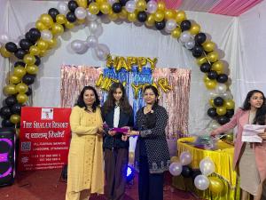 three women standing in front of a arch with balloons at The Shalam Resort श्रीकृष्ण शरणं मम in Lansdowne