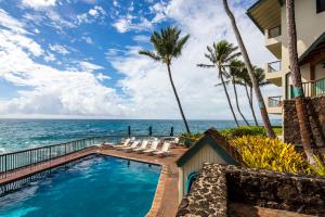 a swimming pool with a view of the ocean at Castle Po'ipū Shores in Koloa