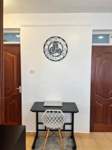 a clock on a wall with a table and a chair at Tranquil Luxury Stay, Utawala, JKIA View in Nairobi