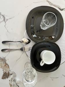 a table with a black plate and a cup and glass at Tranquil Luxury Stay, Utawala, JKIA View in Nairobi