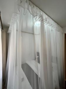 a bedroom with white curtains and a mirror at Tranquil Luxury Stay, Utawala, JKIA View in Nairobi +6 photos