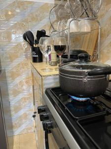 a pot on the stove with two glasses of wine at Tranquil Luxury Stay, Utawala, JKIA View in Nairobi
