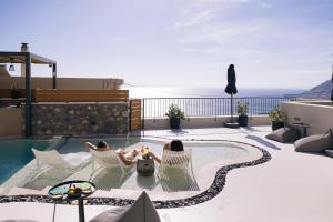 米尔希奥斯Mirthea Suites的两人坐在游泳池旁的椅子上