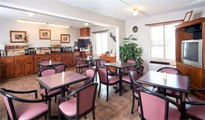 a dining room with tables and chairs and a kitchen at Rest Inn Fort Smith in Fort Smith