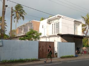 a woman walking down a street in front of a house at Balazo in Ahangama