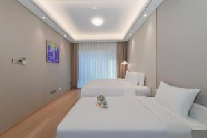 two beds in a hotel room with white sheets at 苏州山塘街华贸姑苏里酒店公寓 in Suzhou