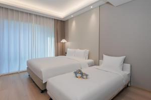 two beds in a hotel room with teddy bears on them at 苏州山塘街华贸姑苏里酒店公寓 in Suzhou
