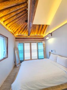 a bedroom with a large white bed and windows at Hanokstay mokhwa in Gyeongju