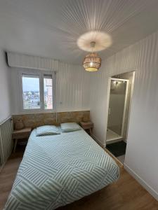 a bedroom with a large bed and a chandelier at Comme à la maison in Saint-Brieuc +1 photo