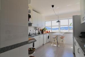 a kitchen with white cabinets and a table with stools at Luxury Condo in Setúbal in Setúbal