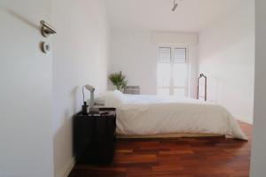 a bedroom with a white bed and a wooden floor at Luxury Condo in Setúbal in Setúbal