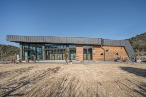 a large brick building with glass doors on a field at Gyeongju Davulchon Pension in Gyeongju