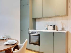 Una cocina con gabinetes blancos y una mesa de madera. en Superb apartment 1BDR 2P - Mairie de Neuilly, en Neuilly-sur-Seine 4 fotos más