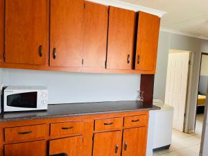a kitchen with wooden cabinets and a microwave on a counter at KINGs' PALACE GUESTHOUSE in Ermelo