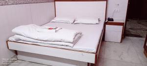 uma cama com lençóis brancos e toalhas em Mother Palace em Nova Deli