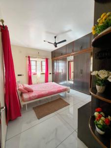 バンガロールにあるYelahanka bungalow 30 mins from airportのベッドルーム1室(ピンクのシーツと赤いカーテンのベッド1台付)