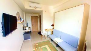 a living room with a blue couch and a flat screen tv at Syariah Apateu Studio - Unit lengkap, tinggal bawa koper! at Apartemen Bandaraya Tallasa City in Pacinongong